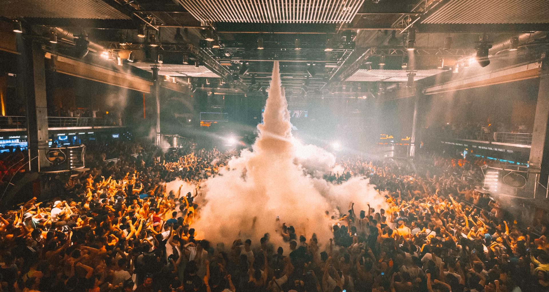 A large crowd at a nightclub with smoke coming out of the roof at Fabrik Madrid