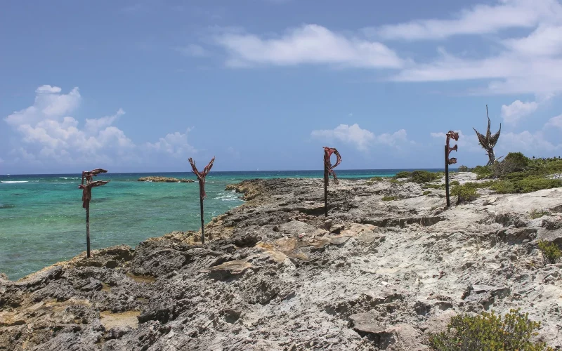 A group of rusty signs on a rocky beach near the ocean for Fyre Festival