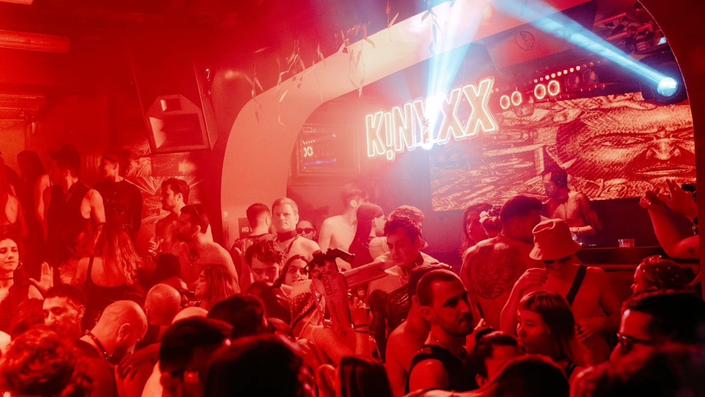 Gente bailando bajo las luces rojas de uno de los clubs techno en barcelona