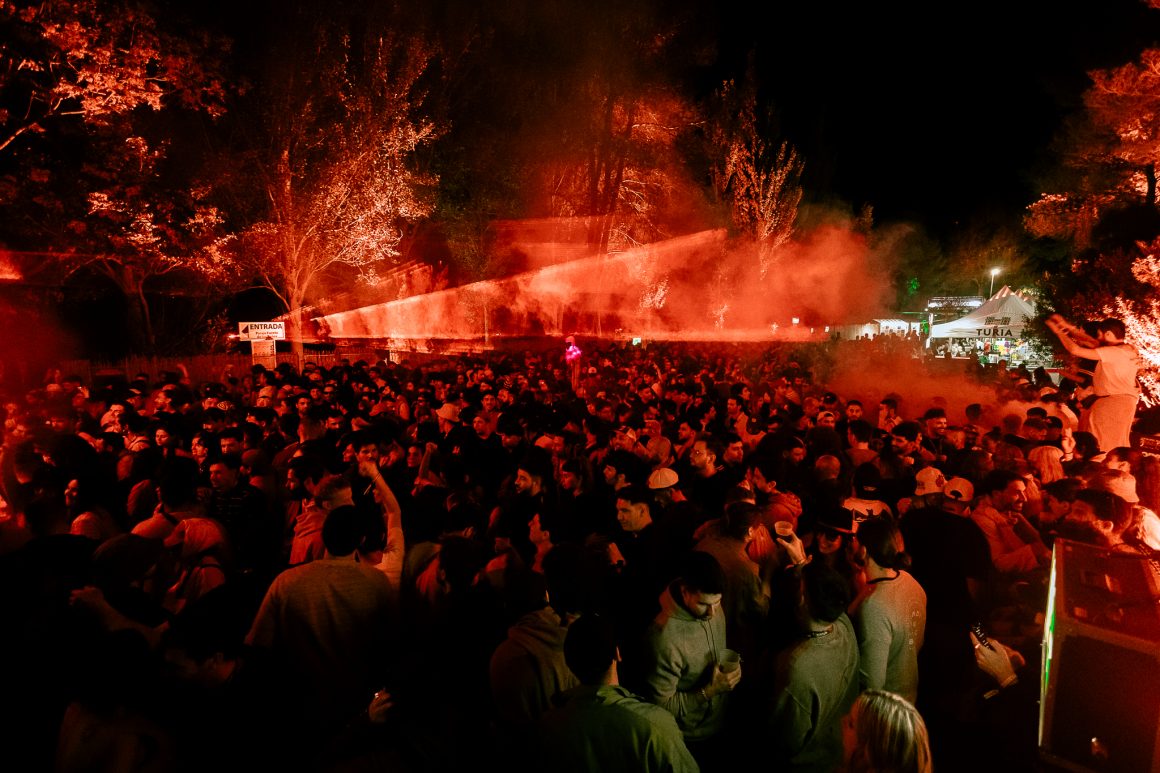 A vibrant night at Días de Campo, with a packed crowd dancing under vibrant red lights in the middle of nature.