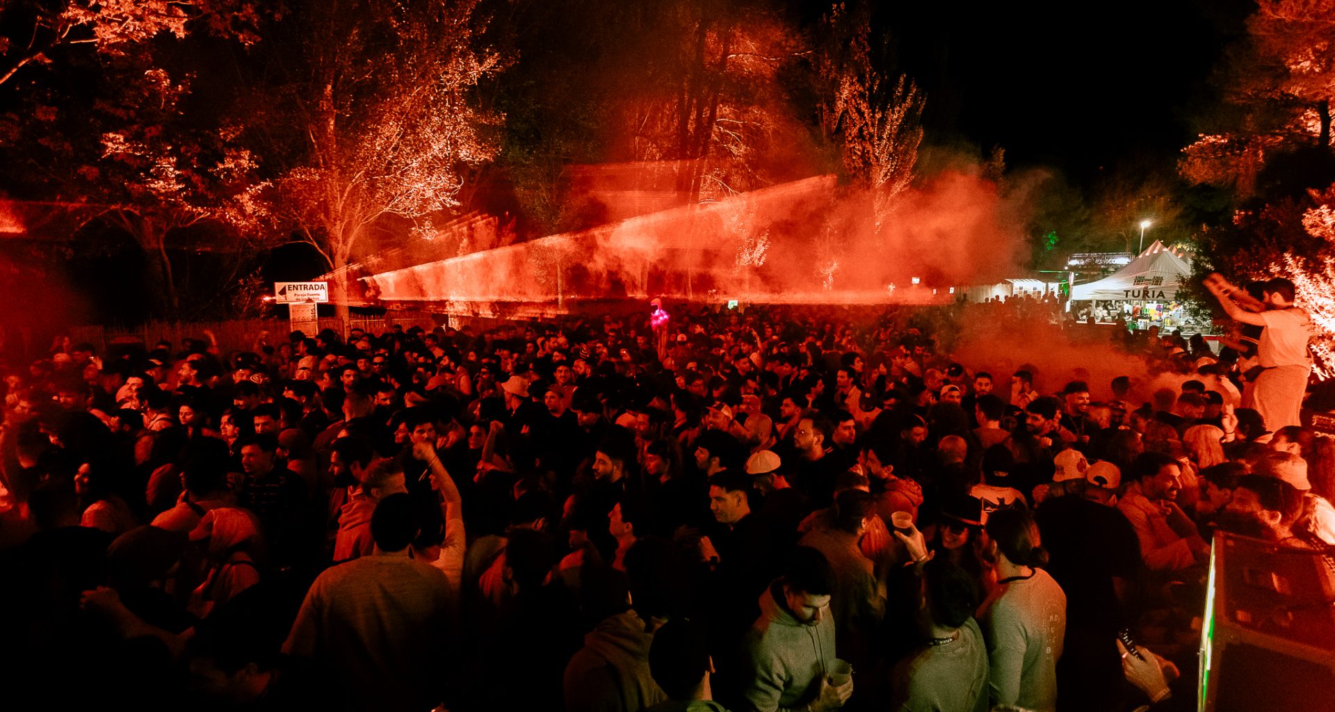 A vibrant night at Días de Campo, with a packed crowd dancing under vibrant red lights in the middle of nature.