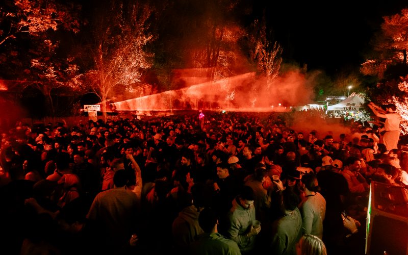 A vibrant night at Días de Campo, with a packed crowd dancing under vibrant red lights in the middle of nature.