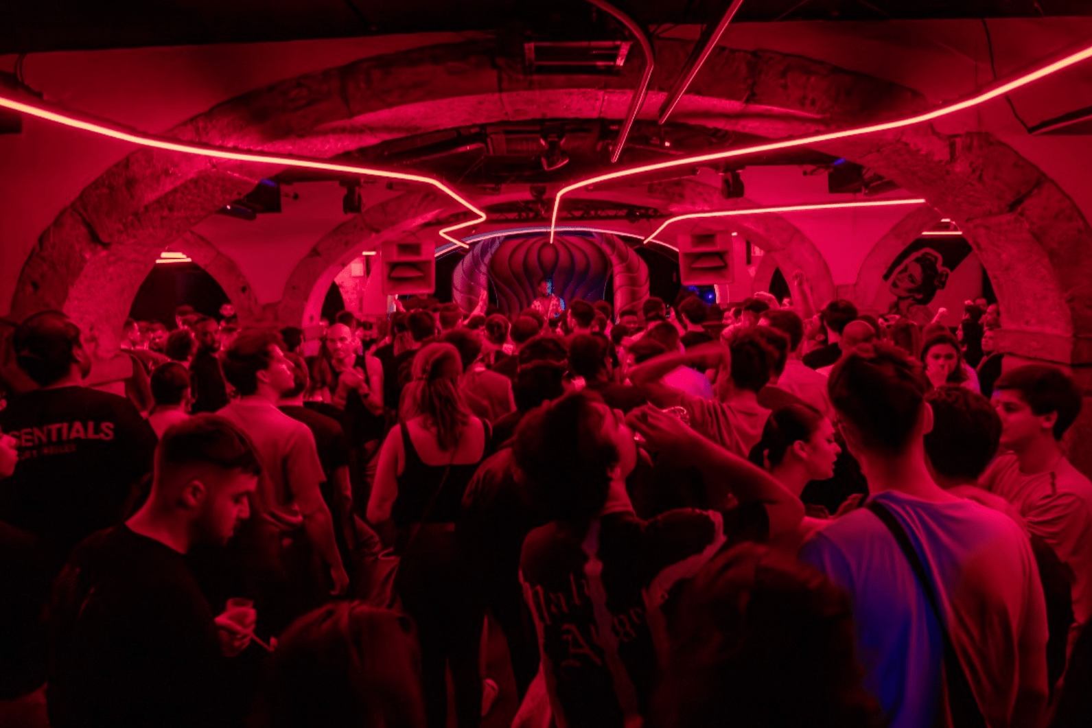 Kremlin nightclub in Lisbon with red neon lights illuminating a crowded dancefloor and arched ceilings.