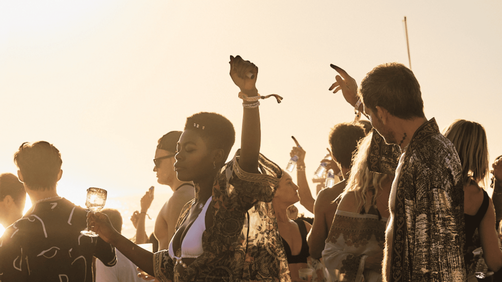 a beautiful woman vibing to the lectronic music at a beach music festival in Lisbon, portugal with crowd around