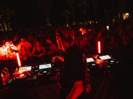 a red and black filtered photo from a club with DJ playing for the crowd at an event by XCEED