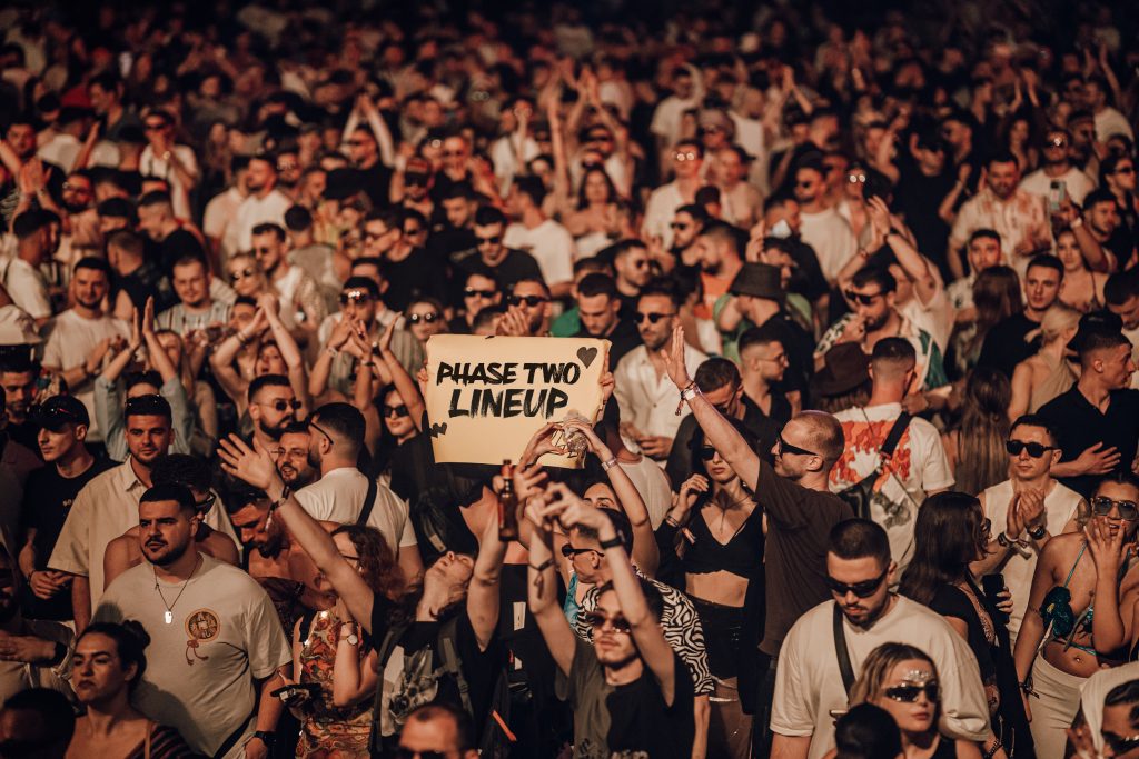 an excited electronic music lover crowd loving the line-up and showing heart gesture to the DJ 