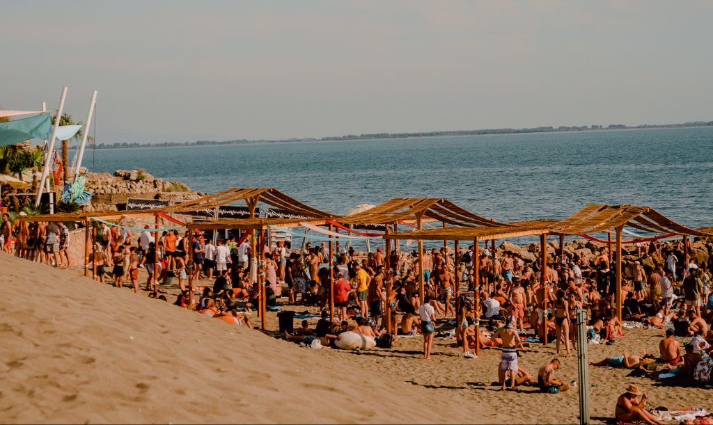 a music festival set between the mountains and beach with white sand, bamboo sheds, good music and summer party festival vibes