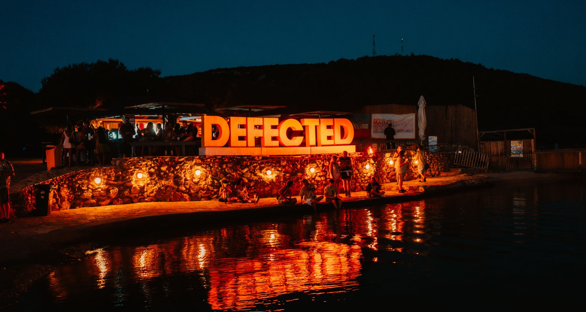 Defected Records Festival sign lighted up by the sea at night in its Croatia edition.