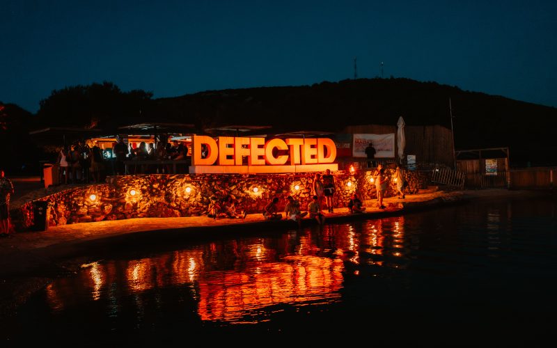 Defected Records Festival sign lighted up by the sea at night in its Croatia edition.