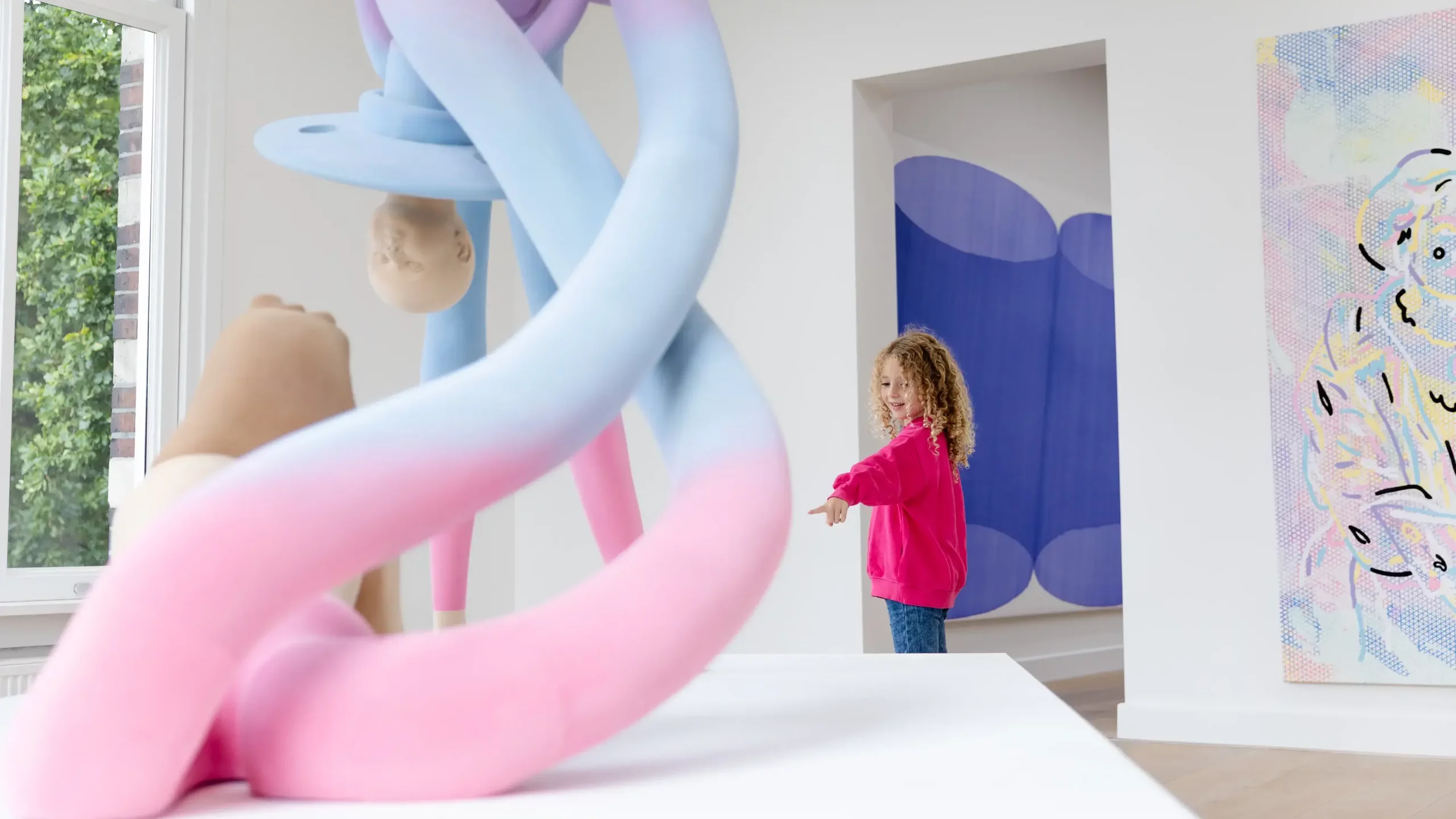A young girl pointing at a large, colorful modern art sculpture in a museum gallery.