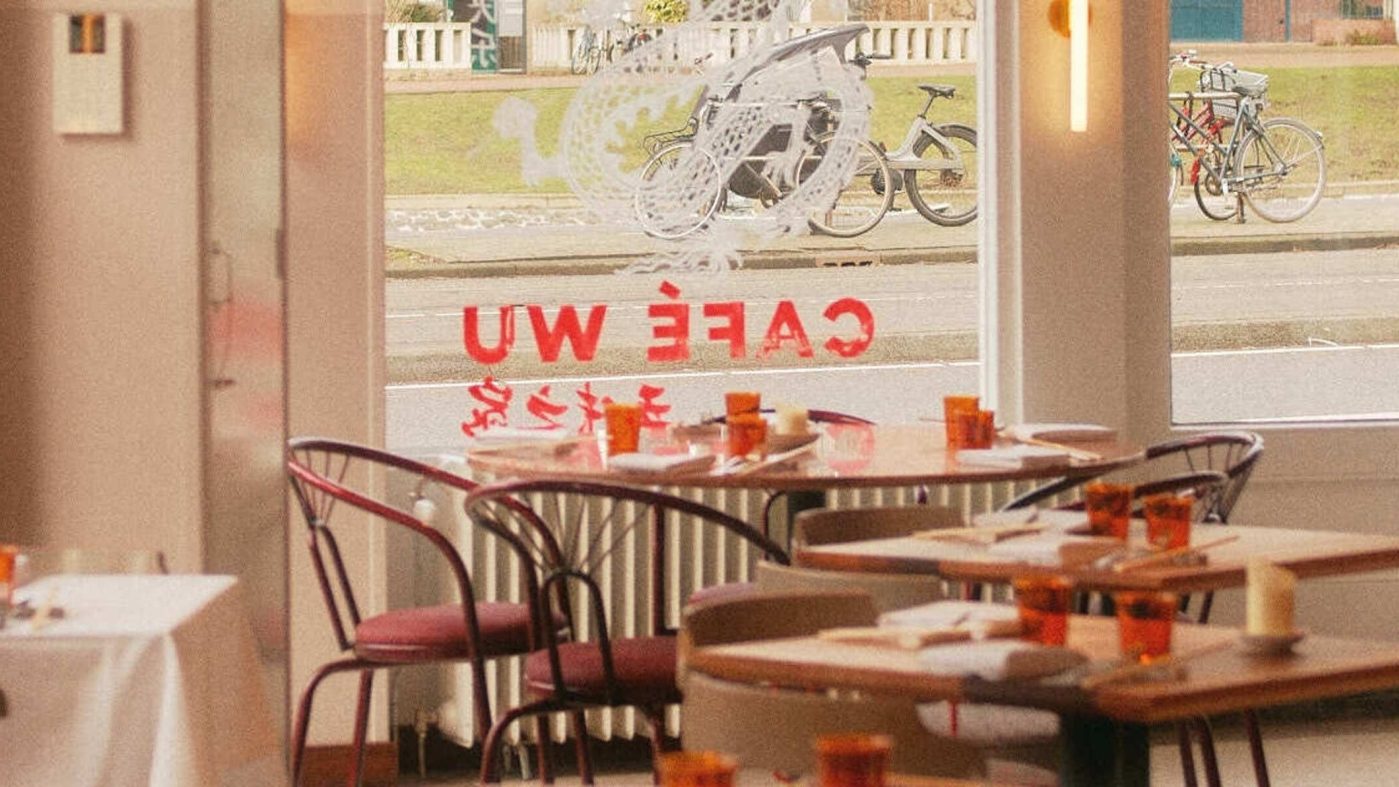 Restaurant interior of Cafe Wu with tables, chairs, and large windows.