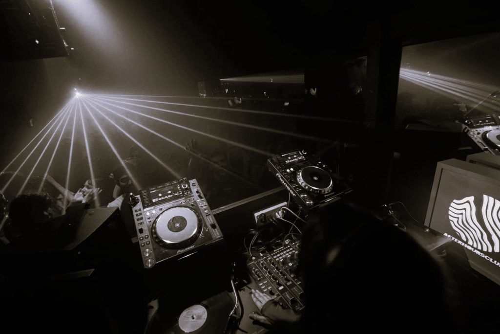 Cabine DJ au Superlove, lasers en éventail au-dessus d’une piste bondée, photo en noir et blanc.