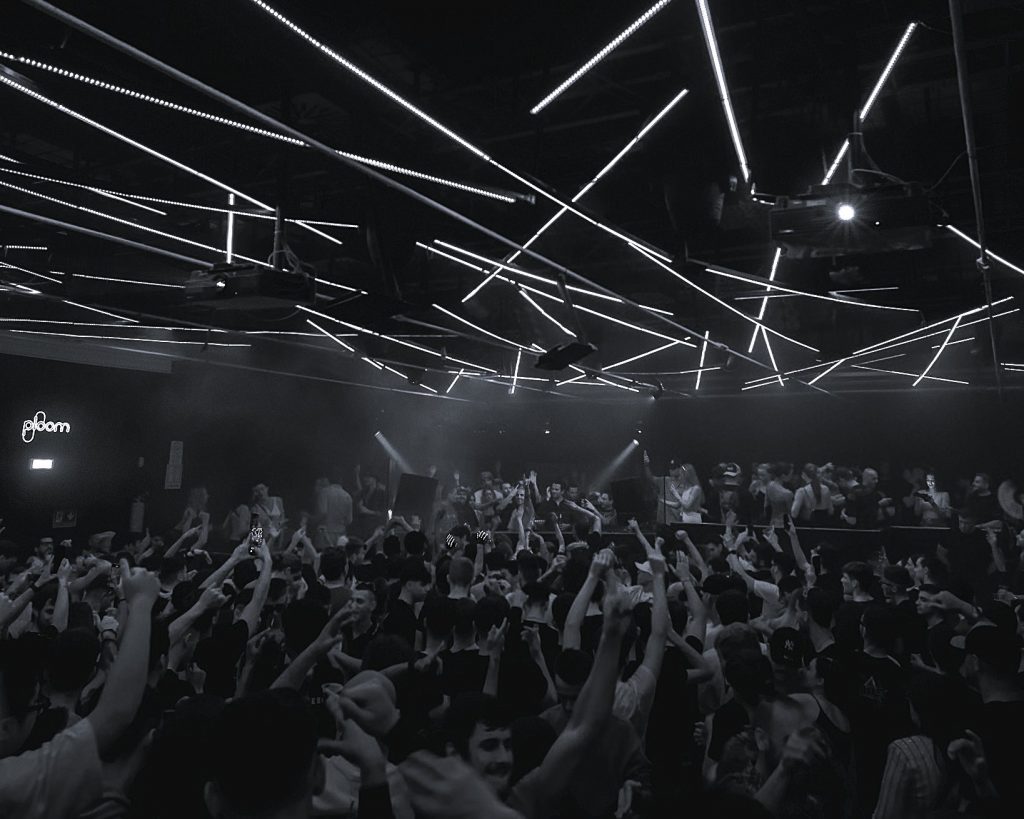 Foule en liesse à Amnesia Milano, plafond tapissé de LED linéaires formant un maillage lumineux au-dessus de la piste.