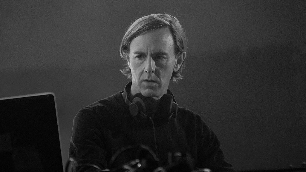 Imagen frontal en blanco y negro de Richie Hawtin pinchando un set de DJ.