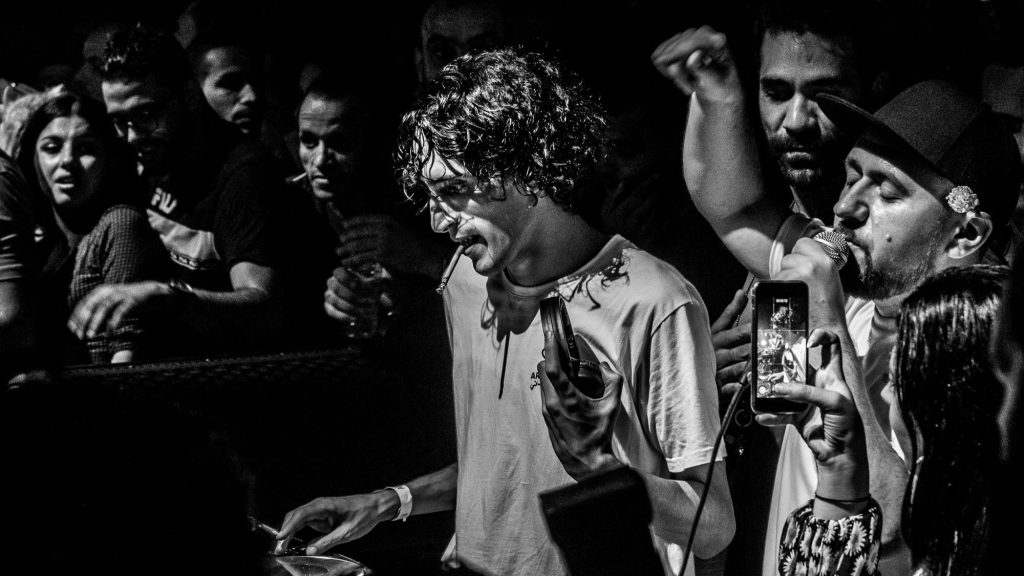 Imagen en blanco y negro de HearThuG pinchando un set de DJ entre el público asistente.