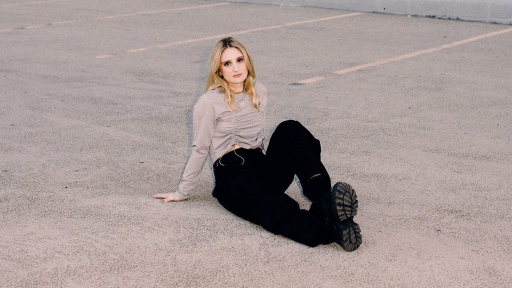 La DJ Carré sentada en el suelo de un parking de coches