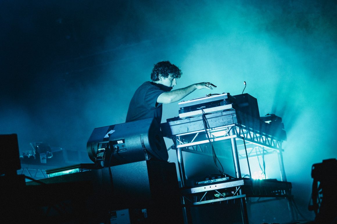 A DJ on stage full of smoke and blue lights