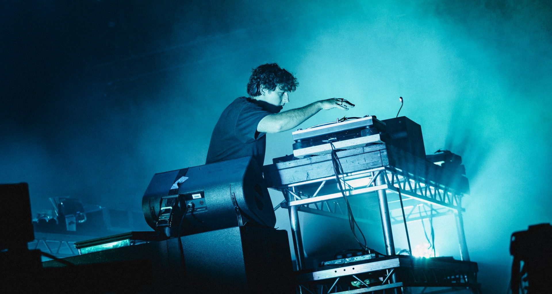 A DJ on stage full of smoke and blue lights