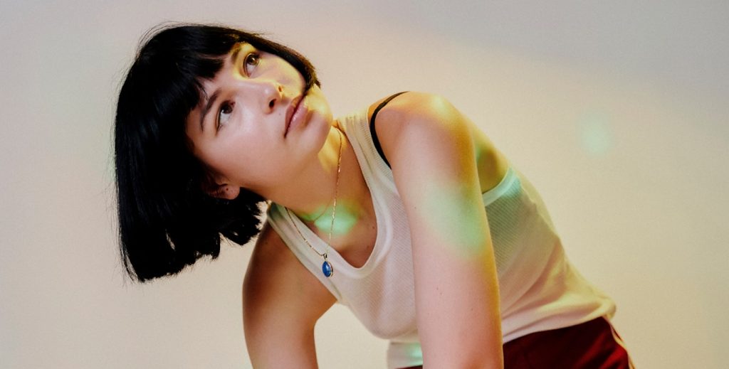 La DJ Kia mirando hacia arriba en un entorno blanco