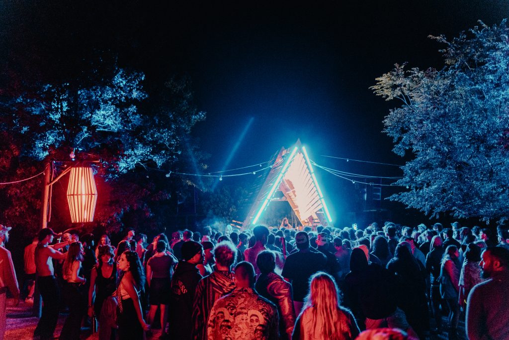 Crowd enjoying a DJ set during the night at Rumours BY The Lake festival in front of a blue led-lit stage