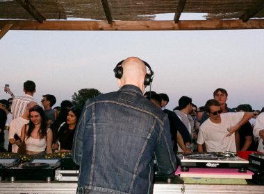 Photo from the back of a DJ booth while DJ is performing in a small open air festival
